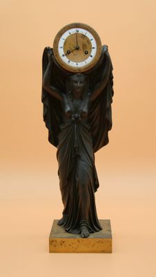 une statue représentant un ange tenant une horloge sur la tête