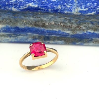 gros plan d'une bague en or avec une pierre en rubis