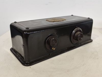 une vieille radio noire posée sur une table près d'un mur blanc