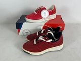 pair of red and white sneakers sitting on top of a box next to a clock