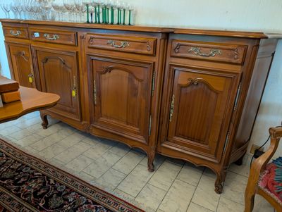 a wooden sideboard with a table and chair in the corner