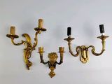 trois appliques murales en laiton fixées sur un mur blanc
