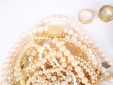 a pile of pearls and gold rings on a white surface