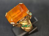 une image représentant une bague en or surmontée d'une pierre orange