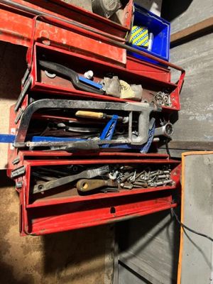 de nombreux outils posés sur une étagère rouge dans un garage