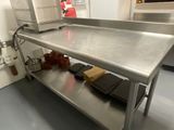 a large stainless steel table in a kitchen with a microwave on it