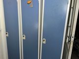 two blue lockers in a bathroom with a toilet