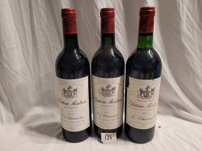 trois bouteilles de vin rouge sont alignées sur une nappe blanche