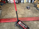 a red jack sitting on the floor in a garage