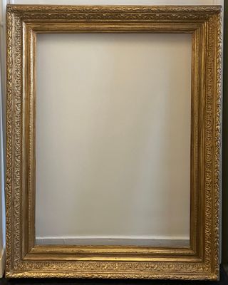 un cadre doré posé sur une table noire, près d'un mur blanc