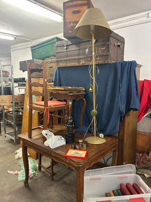 une table sur laquelle est posée une lampe, dans une pièce remplie de meubles