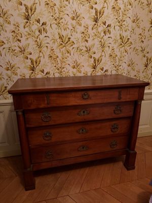 une commode en bois dans une pièce avec du papier peint à motifs floraux