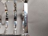 a silver clock that is on a stand on a table