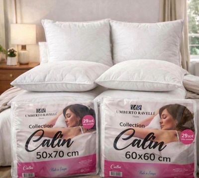 two pillows on top of a bed in a bedroom next to a window