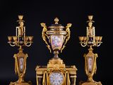 three gold and black vases and a clock on a black surface