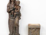 statue of a woman holding a child next to a small box
