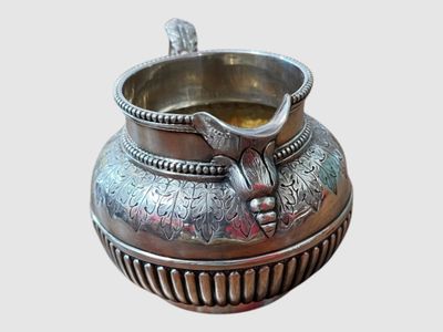 un vase en argent orné d'un oiseau, posé sur une table