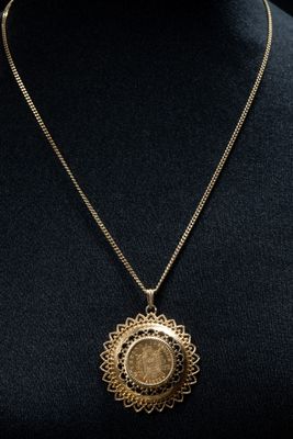a gold necklace with a medallion pendant on a mannequin mannequin mannequin mannequin mannequin mannequin mannequin manne