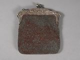 un vieux sac à main en argent avec une anse ornée de perles sur un fond blanc