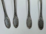 four spoons and a fork are lined up on a white surface
