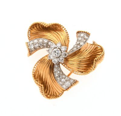 un gros plan sur une broche en forme de nœud, en or et diamants