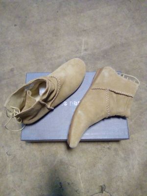 une paire de chaussures en daim beige posée sur une boîte bleue