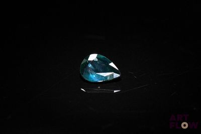 a close up of a tear shaped blue topaze stone on a black surface
