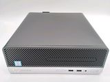 the front of a silver hp desktop computer sitting on top of a white surface