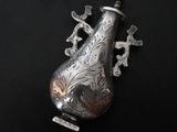 a silver vase with birds on it on a black surface