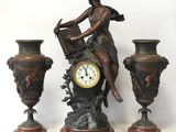 a statue of a woman sitting on top of a clock next to three vases