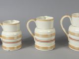 several white and gold vases are lined up against a gray background