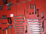 a red wall with a bunch of tools hanging on it