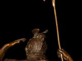 bronze statue of a man holding a sword and a bird on a black background