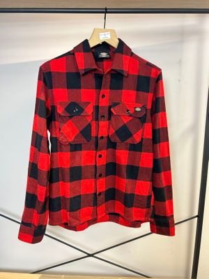 une chemise à carreaux rouges et noirs suspendue à un cintre