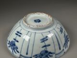 a blue and white bowl with a bird in a cage on it