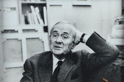 photographie en noir et blanc d'un homme en costume assis à un bureau