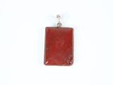 a close up of a red stone pendant on a white surface