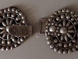 pair of silver plated brooches on a white surface