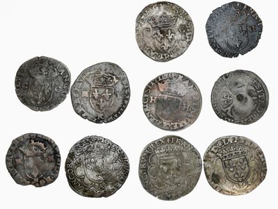Six pièces d'argent de formes et de tailles différentes sont représentées sur une surface blanche.