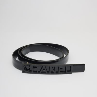 une ceinture en cuir noir avec une boucle en métal et un logo noir