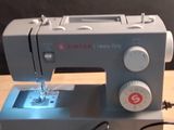 a sewing machine sitting on a wooden table next to a cell phone