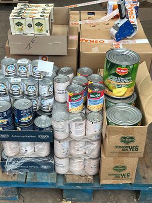 boxes of canned food are stacked on a pallet on the street