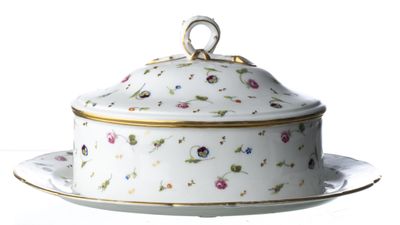 une assiette blanche sur laquelle est posé un plat à couvercle orné de fleurs