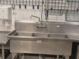 une grande cuisine en inox équipée d'un évier et d'un lave-vaisselle