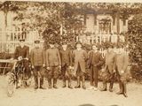 an old photo of a group of men standing in front of a house
