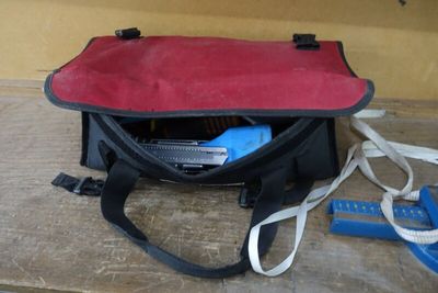 un sac rouge et noir posé par terre à côté d'une paire de ciseaux et d'une paire de ciseaux