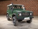 an image of a green land rover parked in front of a brick wall