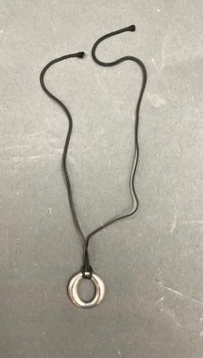 un gros plan d'un collier posé sur une table, muni d'un cordon noir