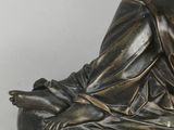 a bronze statue of a man sitting on a rock