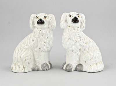 une paire de figurines de chiens en céramique blanche posées sur une surface grise
